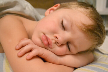 Five years old child sleeping in bed on pillow with a teddy giraffe. High quality photo