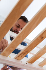 A man is working on a wooden bed frame