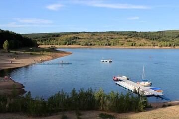Aerial View of Serene Lakeside Beach with Dock and Boats on a Sunny Day