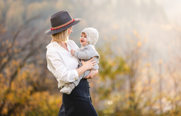 Family happiness mother in hat with her baby in warm clothes on hands in autumn scenery