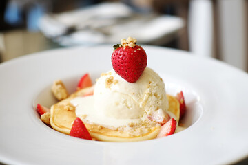 Homemade strawberry pancake with vanilla ice cream on white plate at cafe and bakery shop