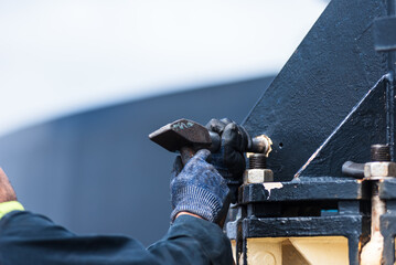 Strong hands clutch heavy hammers, caught mid-swing in the demanding task of knocking out a stubborn pin.