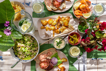 Schön gedeckter Tisch mit Blumensträußen für einen spanischen Abend auf der Terrasse mit Kartoffeln, Burger selbst gemacht Schrimps,garnelen, Bohnensalat, frische Limo