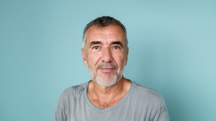 Obraz premium Portrait of a Middle-Aged Man with Grey Hair Against a Light Blue Background