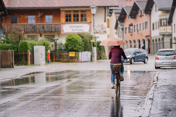 Bavaria, Germany - September 14, 2024 - A person rides a bicycle under an umbrella on a rainy...