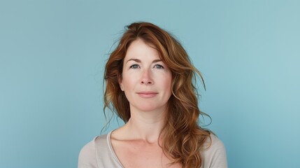 Confident Woman with Wavy Hair in a Casual Portrait Against Blue Background