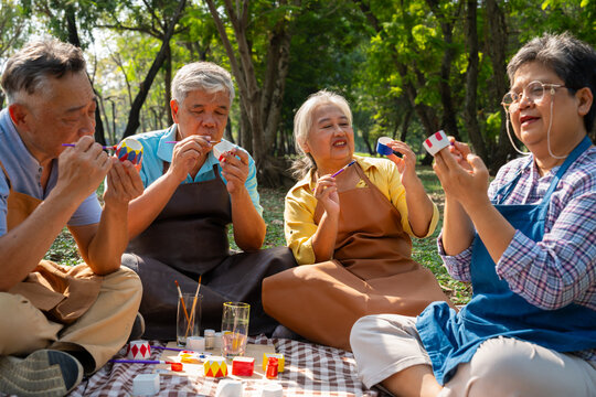 A group of Asian senior people enjoy painting cactus pots and recreational activity or therapy outdoors together  at an elderly healthcare center, Lifestyle concepts about seniority