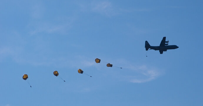 air force military paratroopers dropping from a propellor plane.