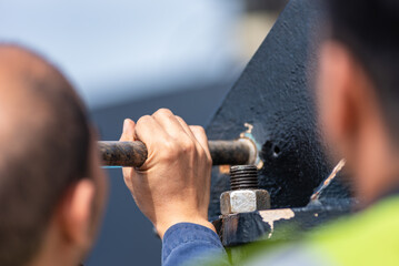 A ship mechanic is absorbed in his task, with the focus sharply on his hand gripping a tool, ready for precise action.