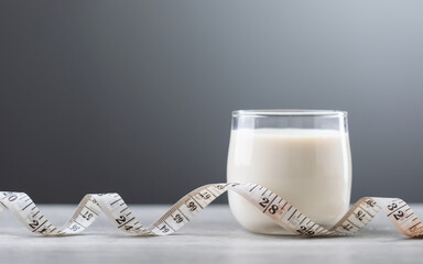 Glass of milk and a measuring tape on the table. Concept of incorporating milk into a healthy diet and fitness plan, highlighting its nutritional benefits for weight management and overall health