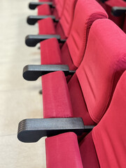 A close-up view of rows of chairs upholstered in red velvet. Vertical image.