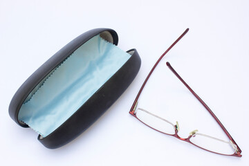 Elegant Eyeglasses Set: This high-resolution image showcases a pair of eyeglasses with thin, reddish-brown frames placed next to an open, black glasses case featuring a light blue interior. 