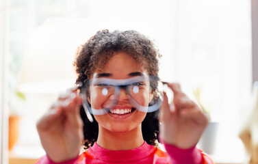 A young African woman smiles and keeps her glasses at home.