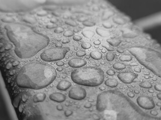 Water drops on a metal surface close view, raindrops on a fence black and white monochrome grayscale photo