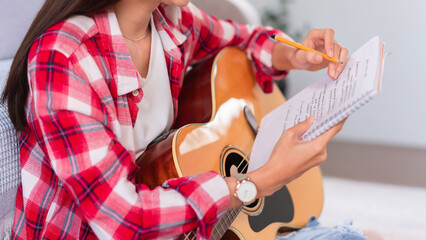Guitar and singer concept, Young woman is composing song while playing acoustic guitar on the floor
