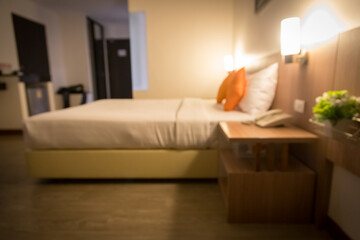 Blurred image of a hotel bedroom with 2 orange pillows, modern and minimalist decor. The bed is soft, clean, good atmosphere