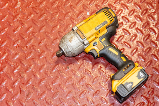 A cordless power tool (impact wrench) used for tightening or loosening bolts, resting on the engine room floor of a merchant ship, ready for operation.