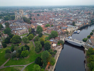 Fototapeta premium Aerial view of York city at dusk. Side view of Lendal bridge over river Ouse. Cars with lights crossing the bridge. Panoramic view of the historic city with Cathedral and Museum gardens.