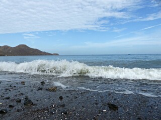 waves crashing on beach with rocks and mountains