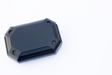 The image features a single black, octagonal-shaped object with a smooth surface and beveled edges. Positioned against a plain white background, the object appears to be made of plastic or a similar s