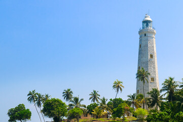 Beautiful white lighthouse Dondra Head, the southernmost cape of Sri Lanka - seen from the beach.