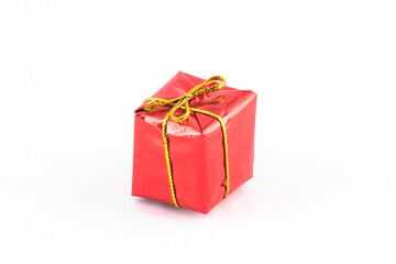 Gift box wrapped in red paper with golden bow isolated on white background