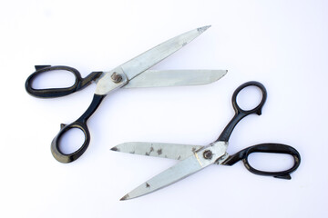 This high-resolution photograph captures an open pair of well-used scissors with black handles against a pristine white background. The wear on the blades suggests frequent use, making this image suit