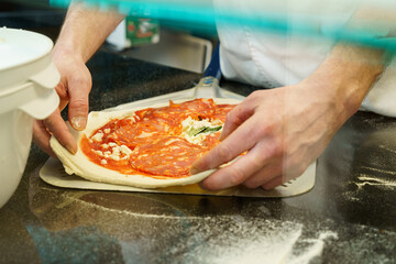 Chef preparing and spreading pizza dough on a pizza shovel before putting it in the oven