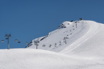 Snowy slopes with chair lift in nice sunny day. Ski resort Gudauri, Georgia. Caucasus Mountains.