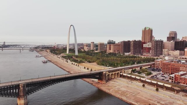 A railroad train coming into downtown Saint Louis, Missouri over the Mississippi River with skyscraper buildings in the background.