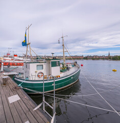 Small green fishing boat at a pier on the island Skeppsholmen, a midsummer day in Stockholm