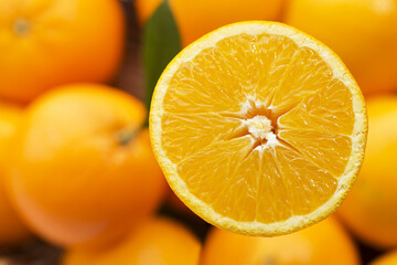 Fototapeta premium A close-up of a juicy orange slice, bursting with vibrant color, against a backdrop of blurred whole oranges.