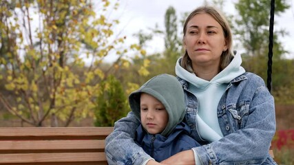 A mother and her son enjoy a relaxing weekend together on a swing, surrounded by nature. They cherish their bond, creating memorable moments in the peaceful park setting.