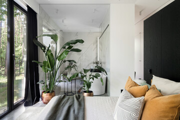 Modern bedroom with private bathroom, featuring glass partition