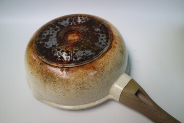 Burnt pan. Back of a charred ceramic frying pan. the bottom of the frying wok pan is brown and charred.