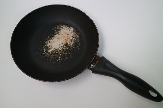 Old scratched non-stick pan isolated on white background. Pan peeling off. there is a possibility of toxic particles and gases, some of them carcinogenic, being released.