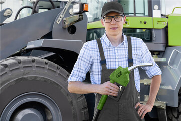 Man with biofuel nozzle on a background of construction machines