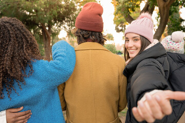 Friends together walking and girl makes a gesture to say come with them. High quality photo
