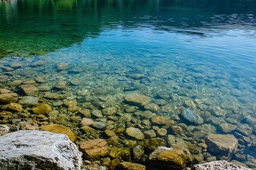 Clear Turquoise Water With River Rocks and Calm Surface