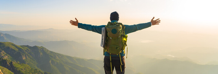 Mountaineer with backpack on shoulders on top of mountain with arms outstretched, travel,...