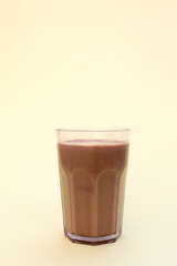 A glass of chocolate milk isolated on yellow background 