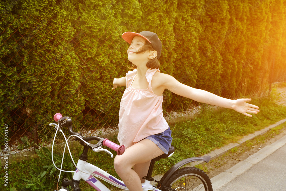 Wall mural young girl cyclist enjoy the beautiful sunrise on summer forest trail. close-up portrait of a happy 