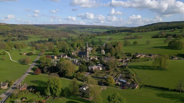 Drone flying over the English village of Edensor surrounded by vast green fields in Derbyshire, UK