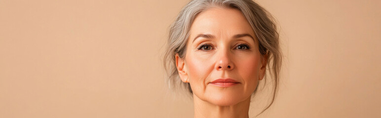 Obraz premium Portrait of serene mature woman with gray hair and light background