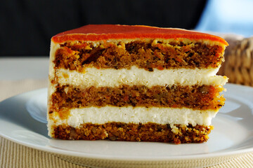 Delicious layers of carrot cake with creamy frosting served on a white plate in a cozy dining setting