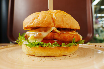 A mouthwatering cheeseburger stacked high with fresh toppings, nestled on a rustic plate ready to be enjoyed in a cozy setting