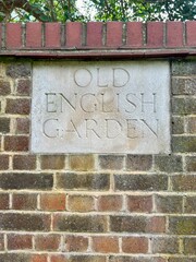 Old English Garden - sign etched in stone on a brick wall. Entrance into an English Garden 