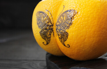 The concept is an imitation of a tattoo in the form of a butterfly applied to two ripe oranges,...