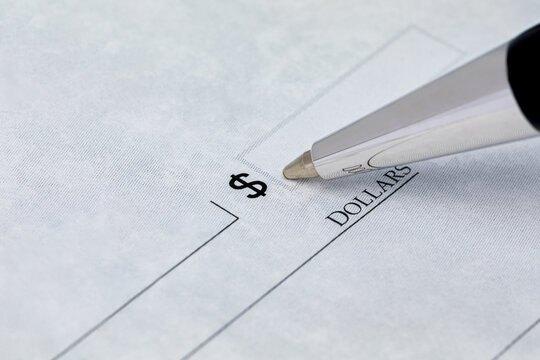 Writing check with pen. Banking, paying bills, and financial fraud concept