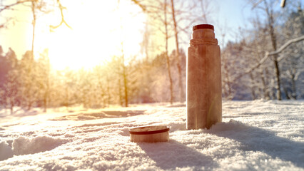 thermos with hot tea or coffee in the winter forest